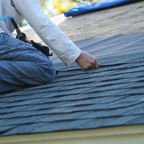 Roofer repairs wind damage.